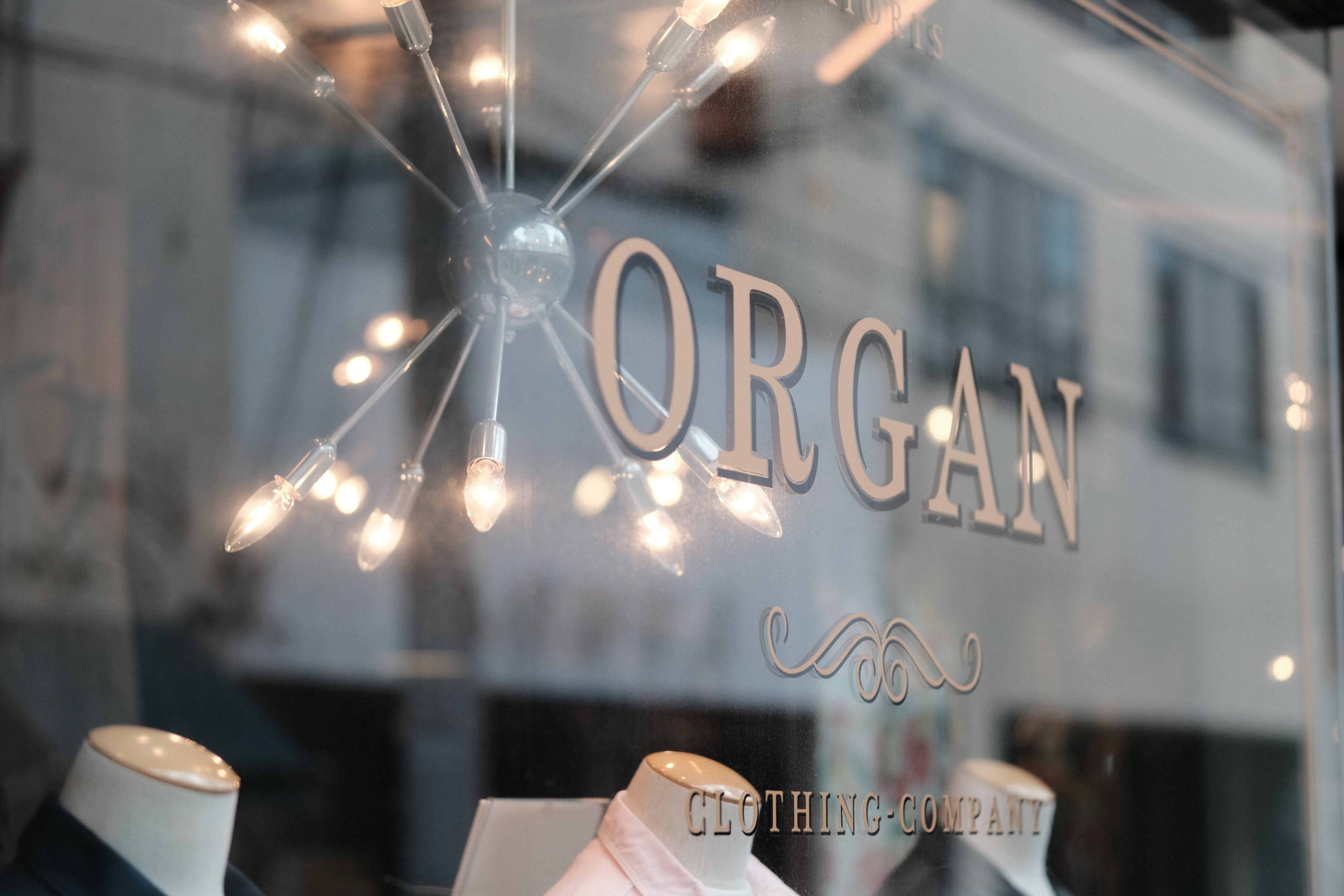 ORGANというロゴが書かれたアパレルショップのショーウィンドウ。スターバースト状のシャンデリアと玉ボケが印象的