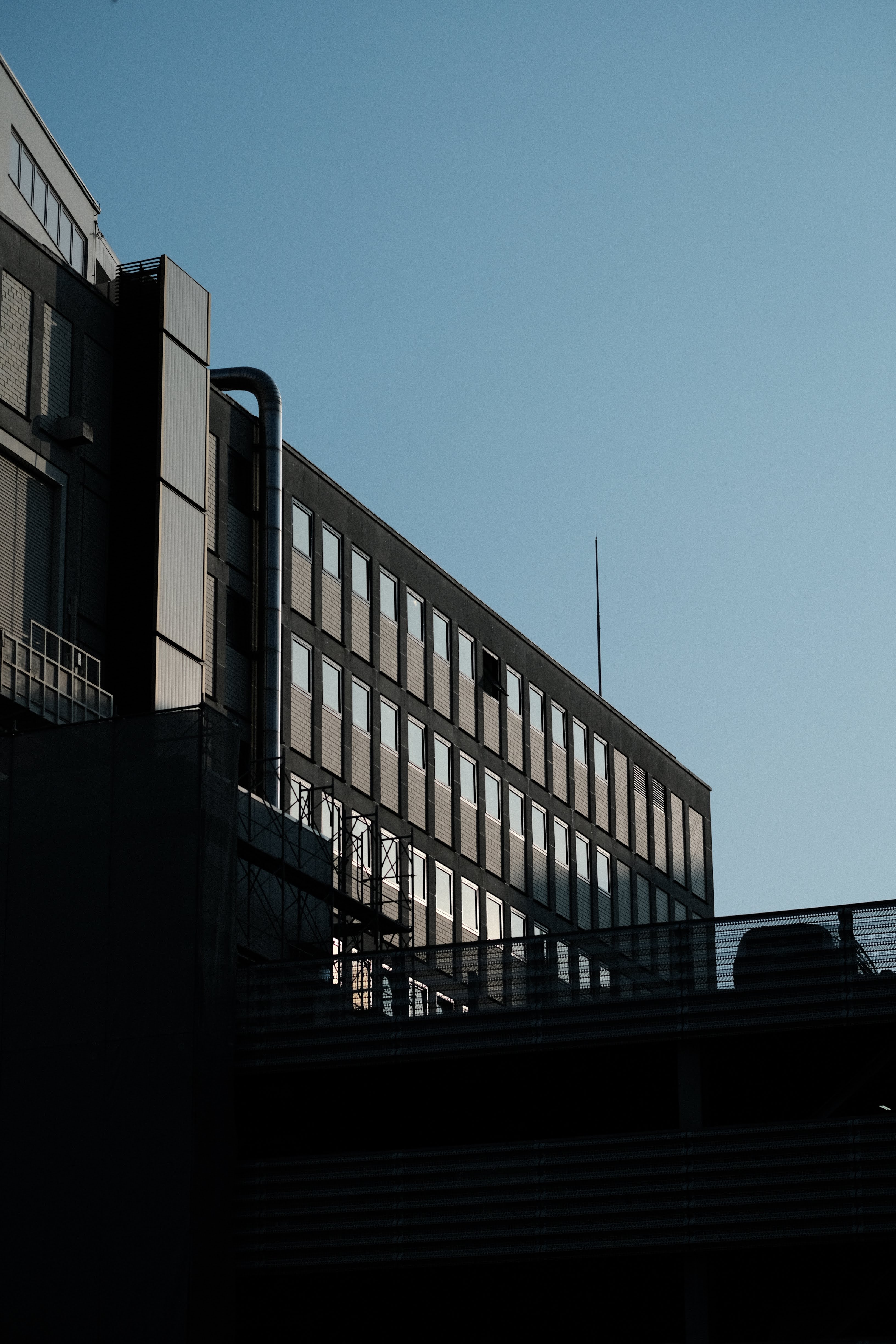 都市のビルディングを下から見上げたアングル。ガラスと鉄骨の外壁が青空に向かって伸びていく構図